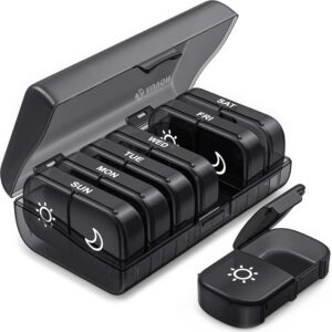 A black weekly pill organizer with seven removable compartments labeled for each day. Each compartment has sun and moon symbols and fits neatly inside a larger storage case with the lid open—perfect for your Amazon wellness finds.