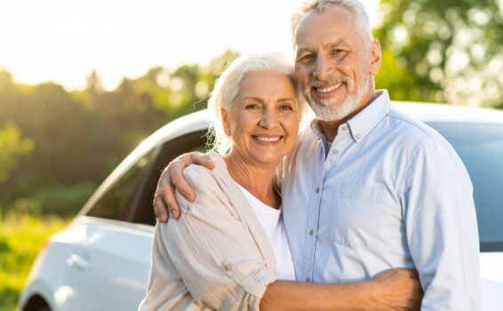 senior couple in front of rental car