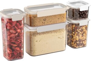 Four clear, rectangular food storage containers with beige lids hold dried strawberries, brown sugar, flour, chocolate chips, and mixed nuts, arranged in a neat row on a white background.