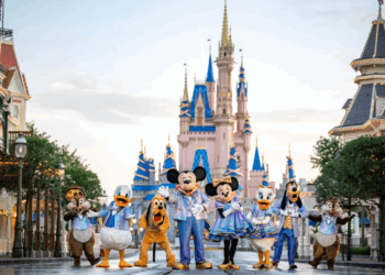 Disney characters like Mickey, Minnie, and Goofy gather in festive outfits before Cinderella Castle, capturing the magic of a multigenerational Disney vacation at the theme park.