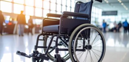 An empty wheelchair sits in a brightly lit airport terminal, sunlight streaming through large windows and blurred travelers in the background—a scene where the best gadgets for traveling with a wheelchair make every journey smoother.