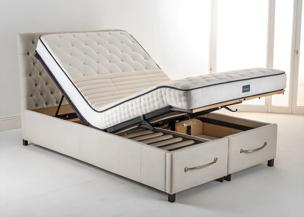 An adjustable upholstered bed with a split mattress, one side elevated, featuring a tufted headboard and two pull-out storage drawers underneath. The bed is in a bright, minimalist room.
