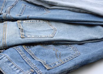 Three pairs of blue jeans in different shades of denim are stacked on top of each other, showing the back pockets and seams—perfect for those seeking the best jeans for women over 50.
