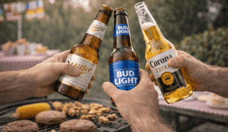 Three hands clink bottles of Miller Lite, Bud Light, and Corona Extra—classic go-to beers by state—over a barbecue grill sizzling with burgers, corn, and skewers in a relaxed outdoor setting.