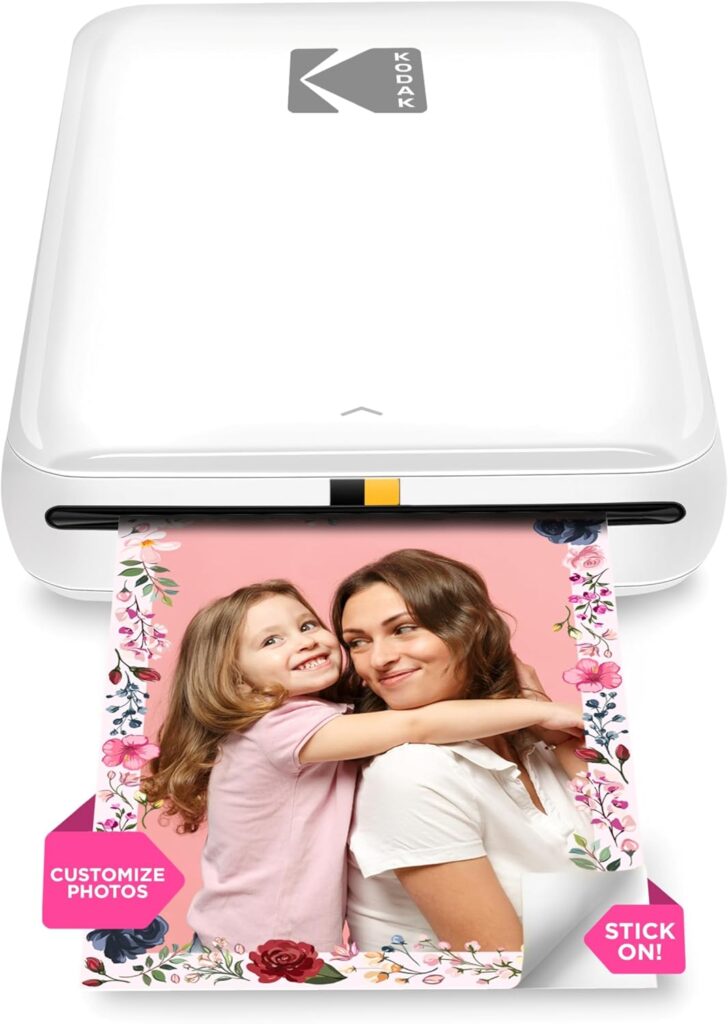 A white Kodak photo printer prints a picture of a smiling woman and child with floral borders. The photo has a pink background and text reading CUSTOMIZE PHOTOS and STICK ON!—perfect for displaying memories or fashion items for teens.