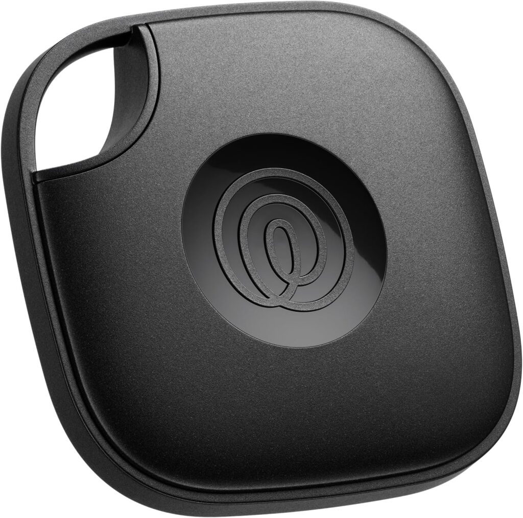 A black, square-shaped Bluetooth tracker with rounded edges and a circular button in the center featuring the at symbol—perfect for attaching to keychains or fashion items for teens, thanks to its stylish design and handy cutout in one corner.