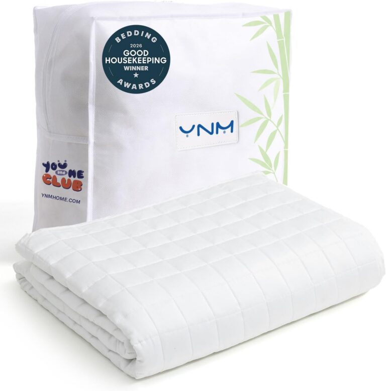 A folded white weighted blanket with a quilted pattern sits in front of its packaging, which features the YNM brand logo, bamboo leaf graphics, and a Good Housekeeping 2020 Bedding Awards badge—one of the menopause must haves for restful sleep.