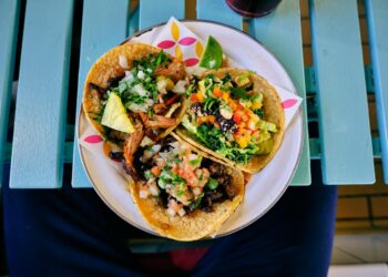 Three tacos with avocado, salsa, lime