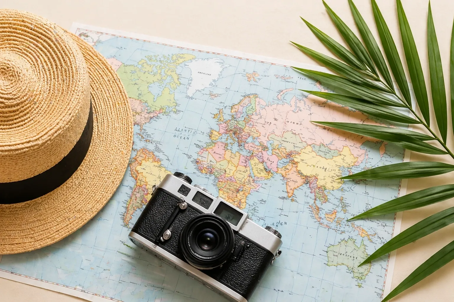 A straw hat, a vintage camera, and a green palm leaf rest on a colorful world map, suggesting themes of travel and adventure—perfect inspiration to ask a travel agent about your next journey.
